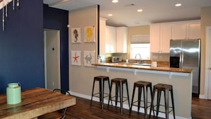 Eine moderne Küche mit einer zentralen Kochinsel, Barhocker und einem Esstisch.