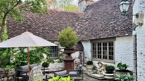 Ein traditioneller Innenhof mit Steinsitzen, einem großen Sonnenschirm und Kübelpflanzen.