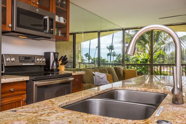 A kitchen with a stainless steel sink, a coffee maker, and a microwave.