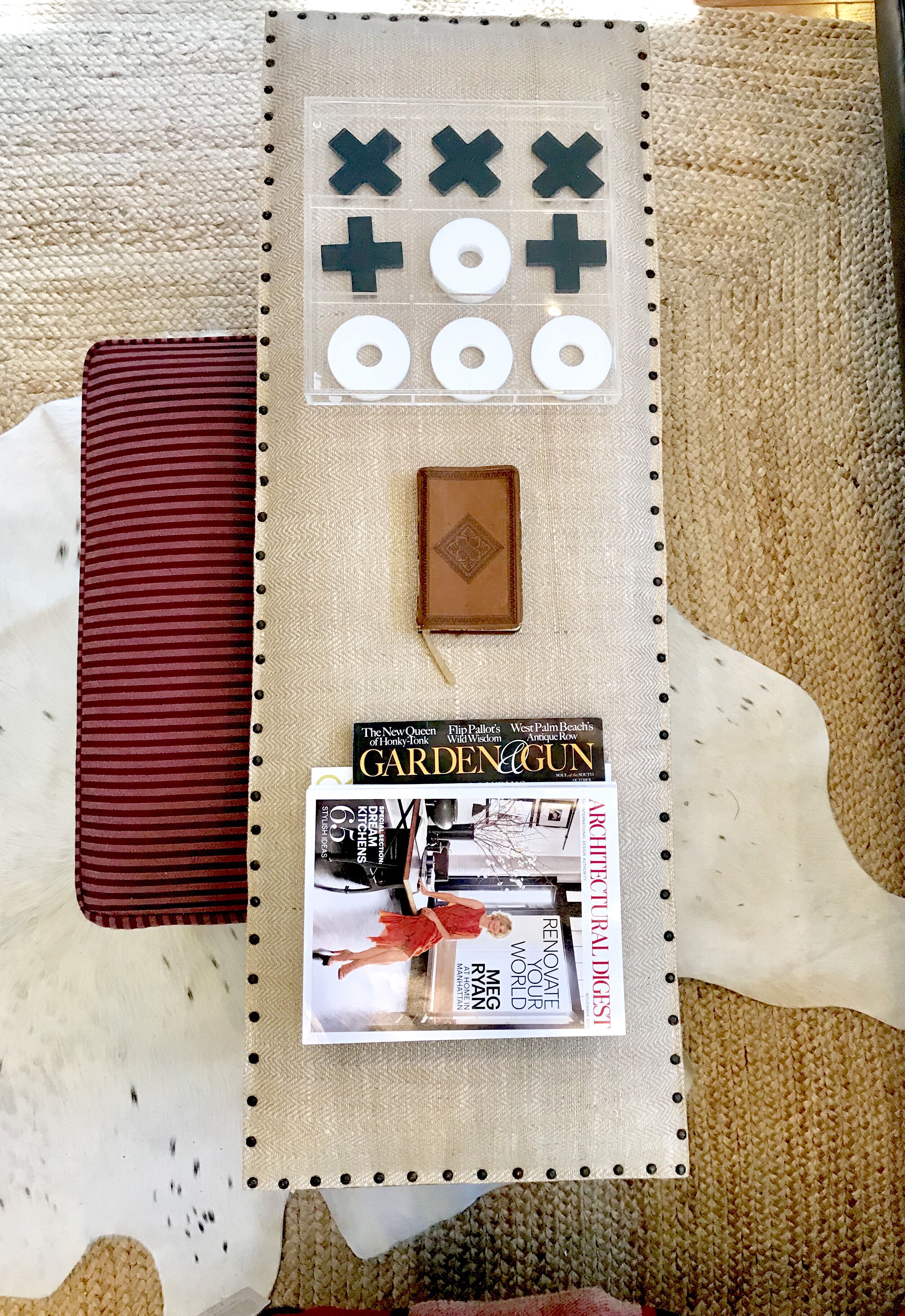 A bulletin board with a game board, a leather-bound book, and a magazine titled "GARDEN & GUN".