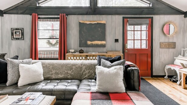 Ein gemütliches Wohnzimmer mit einer Ledersofa, einem Holztisch und einer roter Tür.