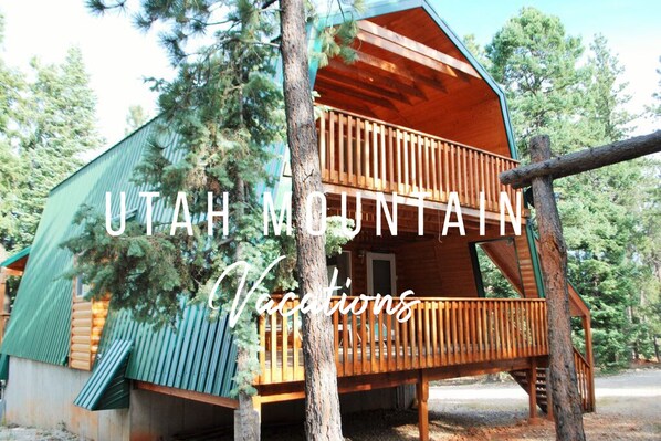A wooden cabin with a balcony, surrounded by trees.