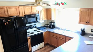 Una cocina con gabinetes de madera, un refrigerador negro, una estufa y un microondas.
