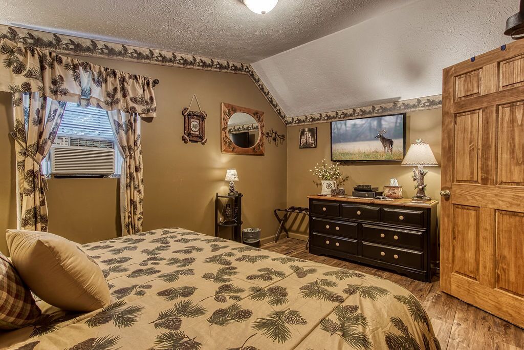 Une chambre à coucher avec un lit, une commode, un miroir et une porte.
