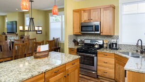 A kitchen with wooden cabinets, granite countertops, a stainless steel stove, and a microwave.