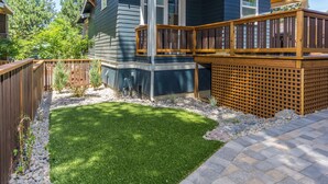 A backyard with a well-maintained lawn, a wooden deck, and a stone pathway.