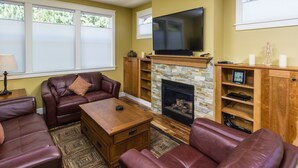 A living room with leather sofas, a fireplace, a flat-screen TV, and a stone accent wall.