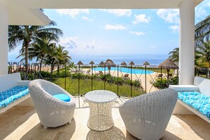 A balcony with wicker furniture, a pool, and a view of the beach and ocean. - Views, Views, Views!! (Puerto Morelos)