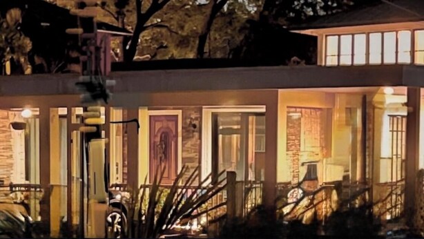 A modern house with a well-lit entrance, large windows, and a visible door. - Tropical, private, downtown (Sarasota)
