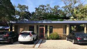 A building with a modern design, a red door, and two parked cars in front. - Tropical, private, downtown (Sarasota)