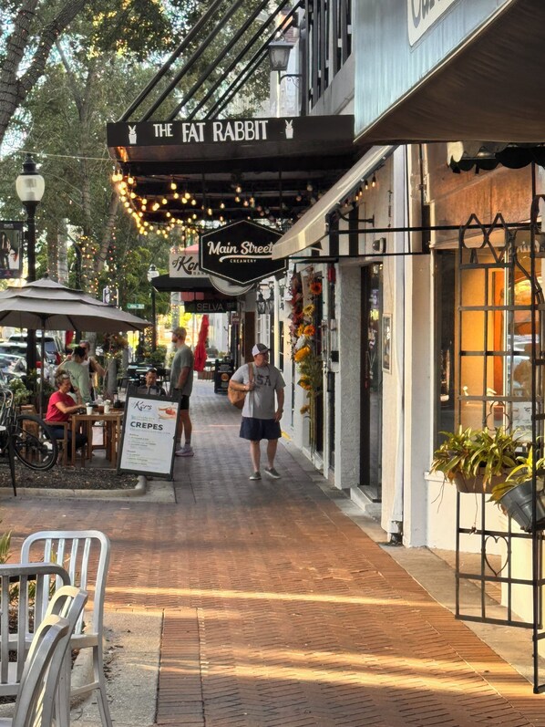 A street with outdoor seating, a cafe named 'The Fat Rabbit', and a creamery called 'Main Street Creamery'.