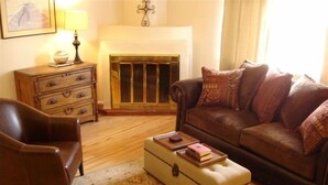 Un salon chaleureux avec un canapé en cuir, une commode en bois, une lampe et une cheminée.