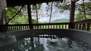 A hot tub with a view of a forested hillside.