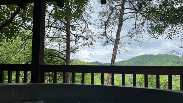 A hot tub with a view of a forested hillside.
