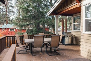 An outdoor patio with a wooden deck, a table with chairs, and a grill. - Amazing West Side * 2 King Suites * Walk Everywhere * 8 Person Hot Tub (Bend)