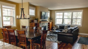A spacious living area with a dining table, chairs, a sofa, and a fireplace. - Amazing West Side * 2 King Suites * Walk Everywhere  * 8 Person Hot Tub (Bend)