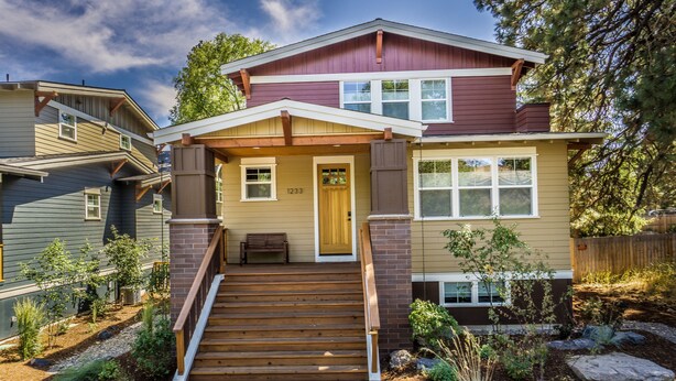 A two-story house with a front porch, a wooden staircase, and a well-maintained garden. - Amazing West Side * 2 King Suites * Walk Everywhere  * 8 Person Hot Tub (Bend)