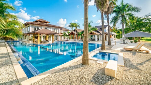 Ein Resort mit großem Pool, Palmen und blauem Himmel.