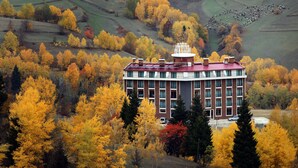 Un edificio de varios pisos con techo rojo, rodeado de árboles de colores otoñales.