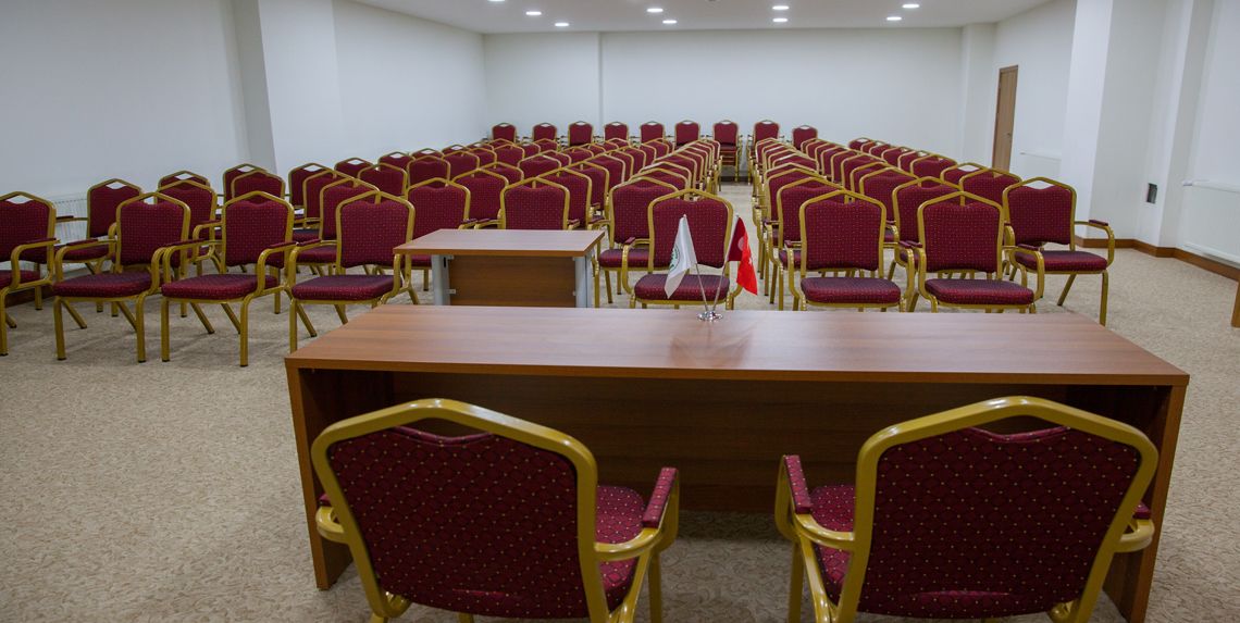 Une salle de conférence avec une longue table et des rangées de chaises.