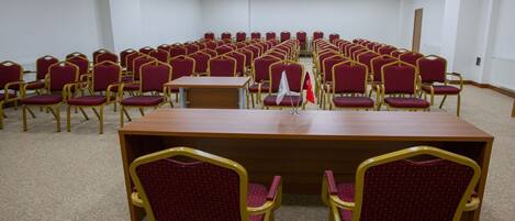 Une salle de conférence avec une longue table et des rangées de chaises.