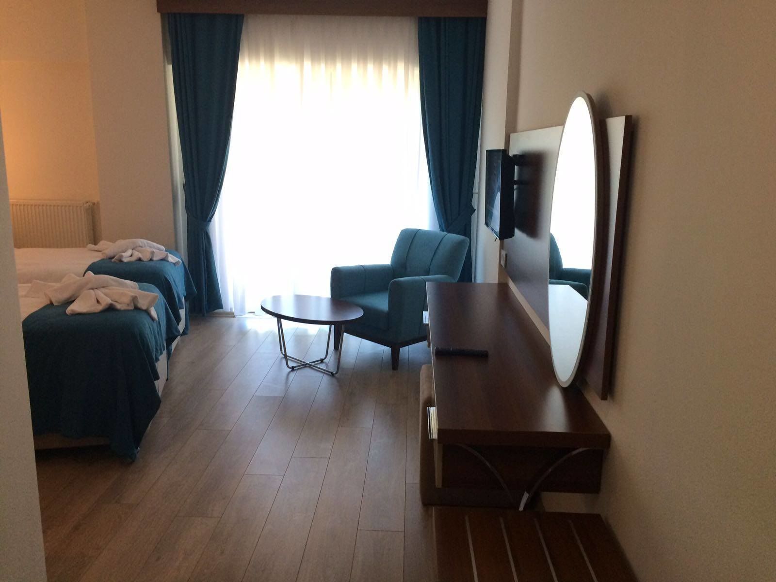 A hotel room with two beds, a sofa, a small table, and a TV.