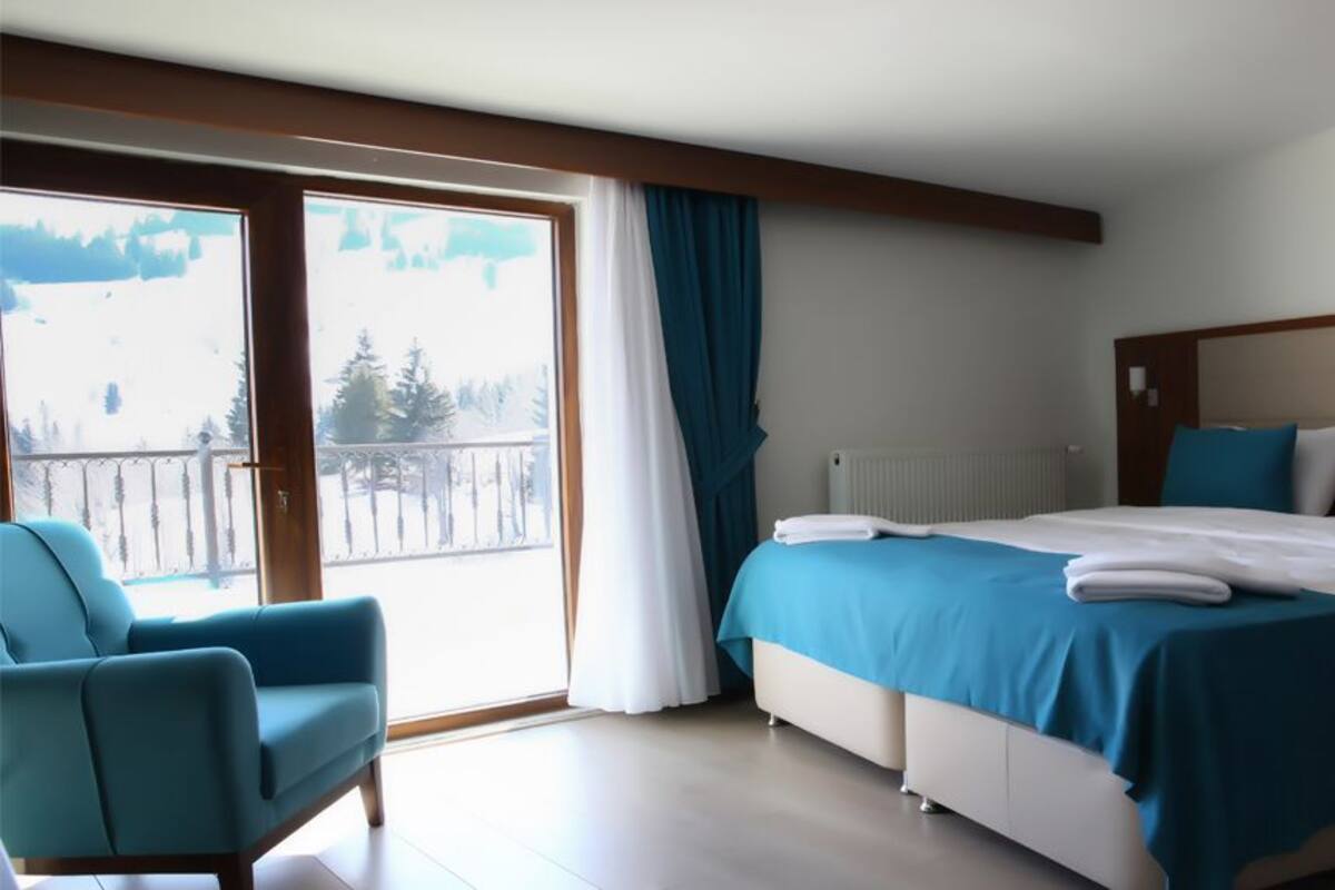 A hotel room with a large bed, a chair, a view of a snowy landscape through a sliding door, and a radiator.