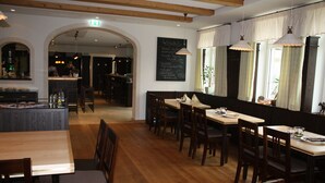 En restaurant med træborde og -stole, et barområde og en menu på tavle.