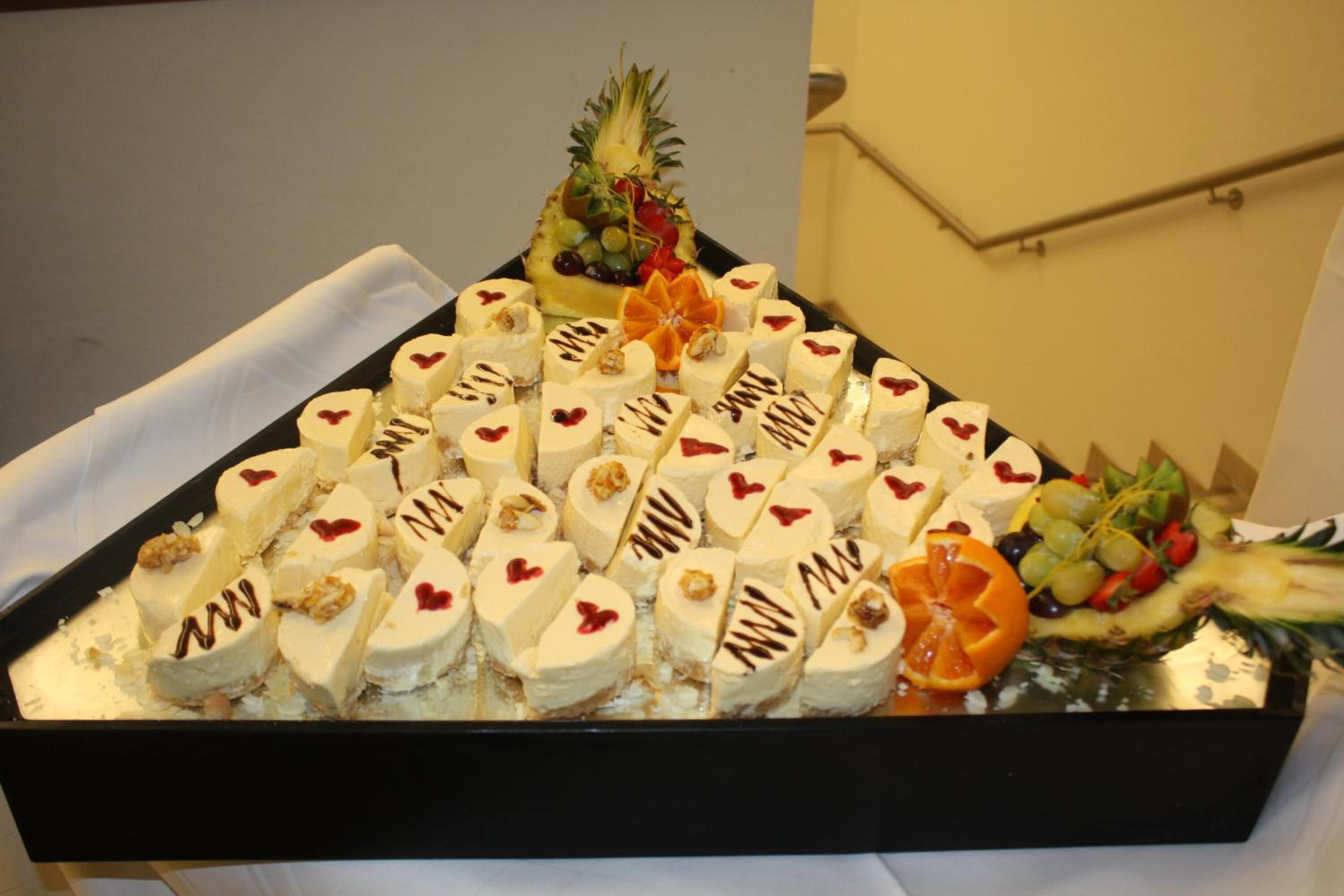 Un plateau rempli de desserts en forme de cœur et un ananas décoratif au centre.
