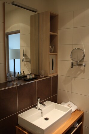Une salle de bain avec un lavabo blanc, un miroir et un meuble-lavabo en bois.
