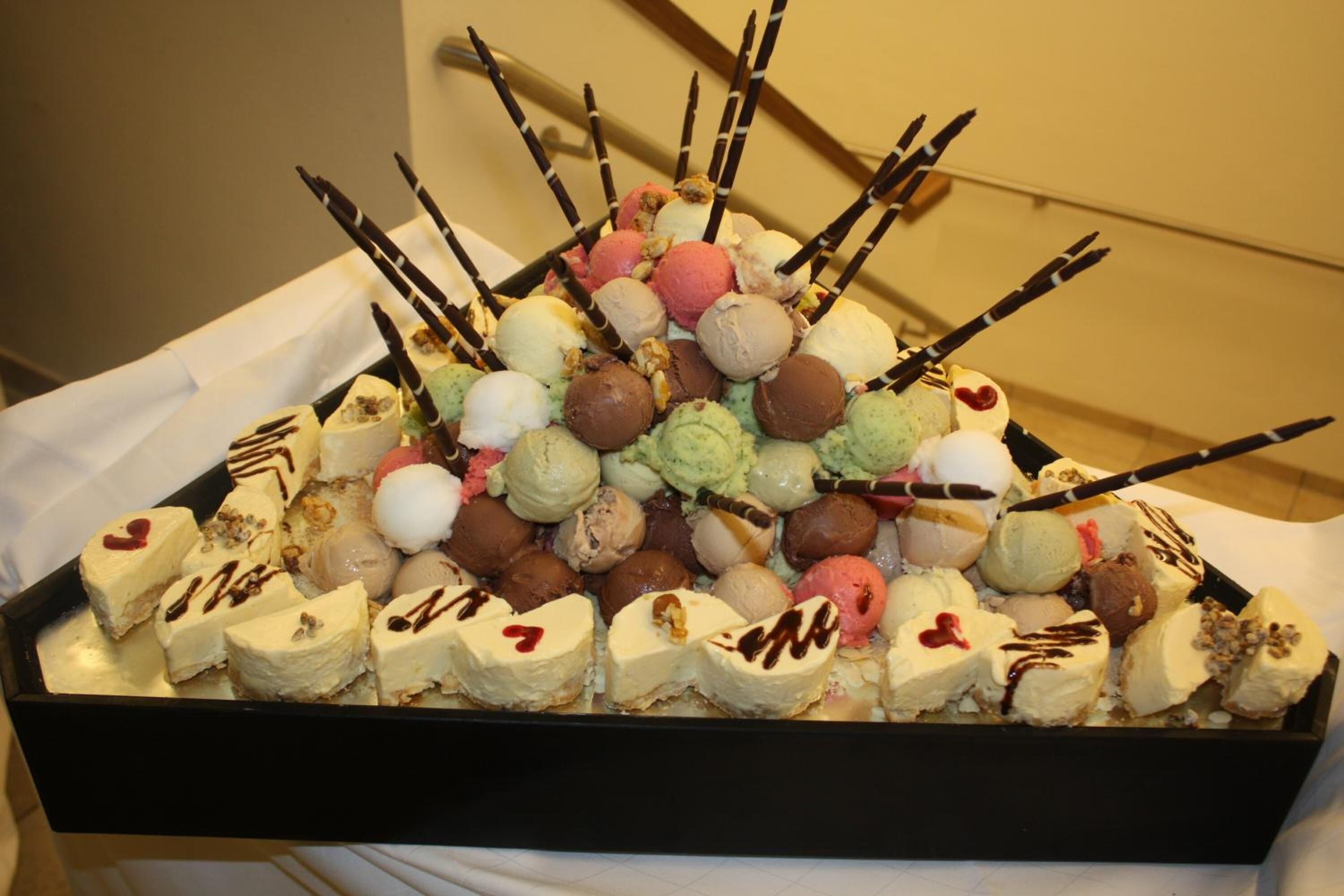 Un plateau contenant un assortiment de glaces et de desserts, avec différentes saveurs et garnitures, disposés sur un plateau noir.