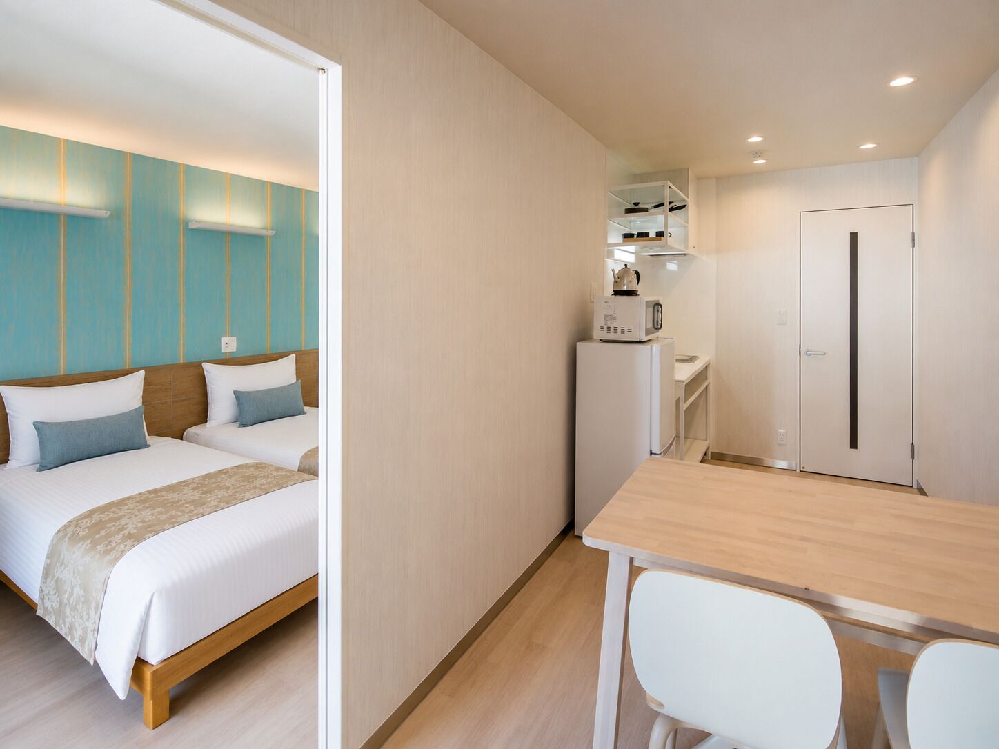 A hotel room with a bed, a small kitchenette, and a dining area.