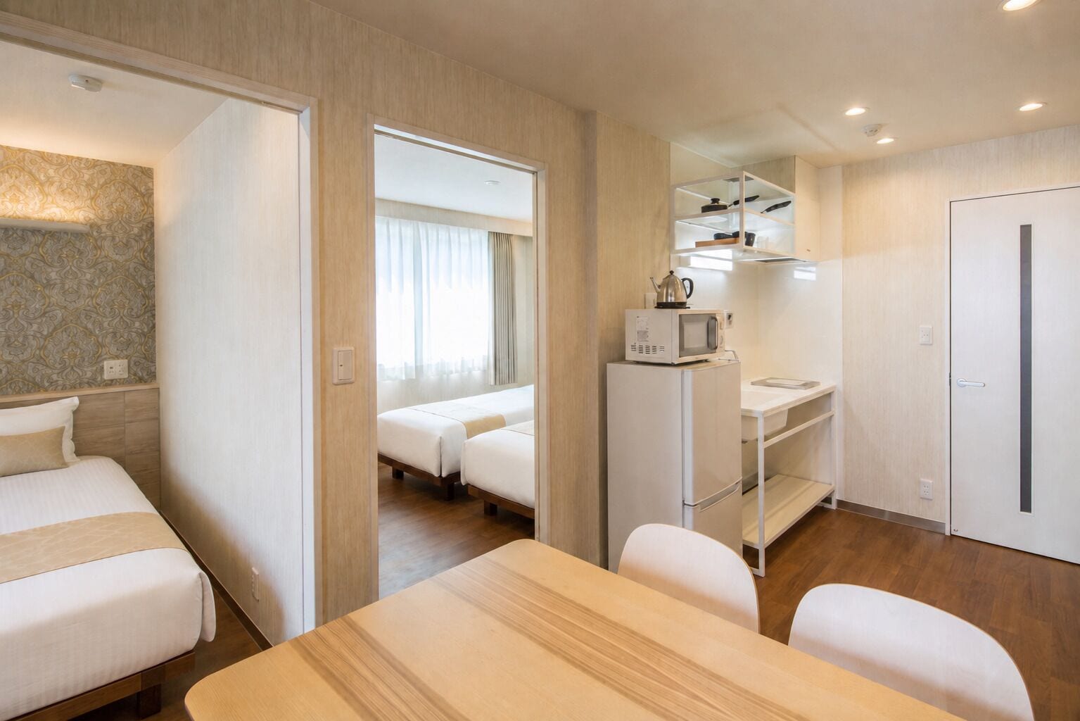 Ein Hotelzimmer mit einem Bett, einem Esstisch, einer Küchenzeile mit Mikrowelle und einem Kleiderschrank.