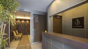 Ett modernt receptionsområde med en receptionsdisk i trä, en bokhylla och två stolar.