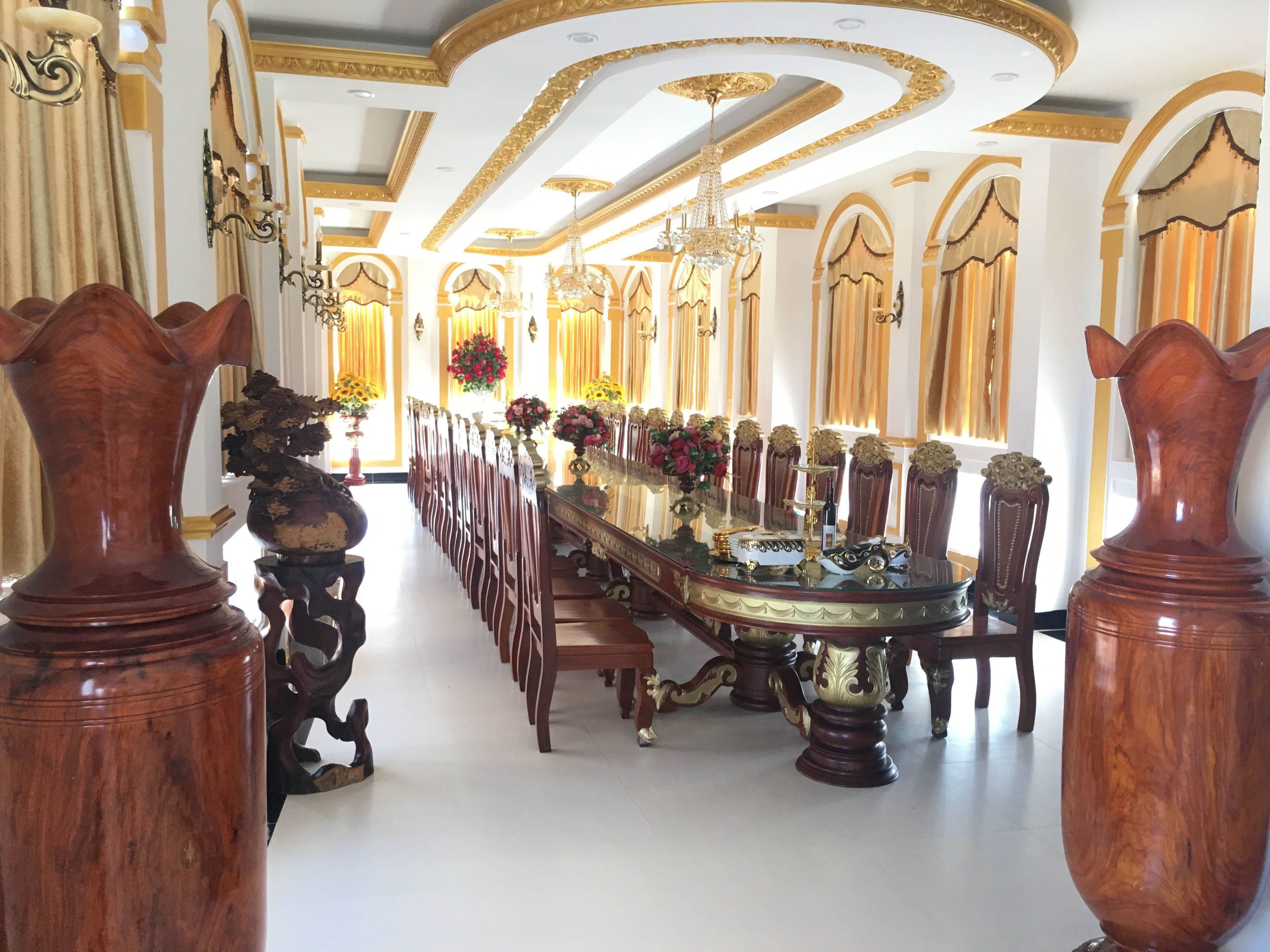 Un comedor amplio con sillas de madera adornadas, una mesa larga y decoraciones elaboradas en el techo.
