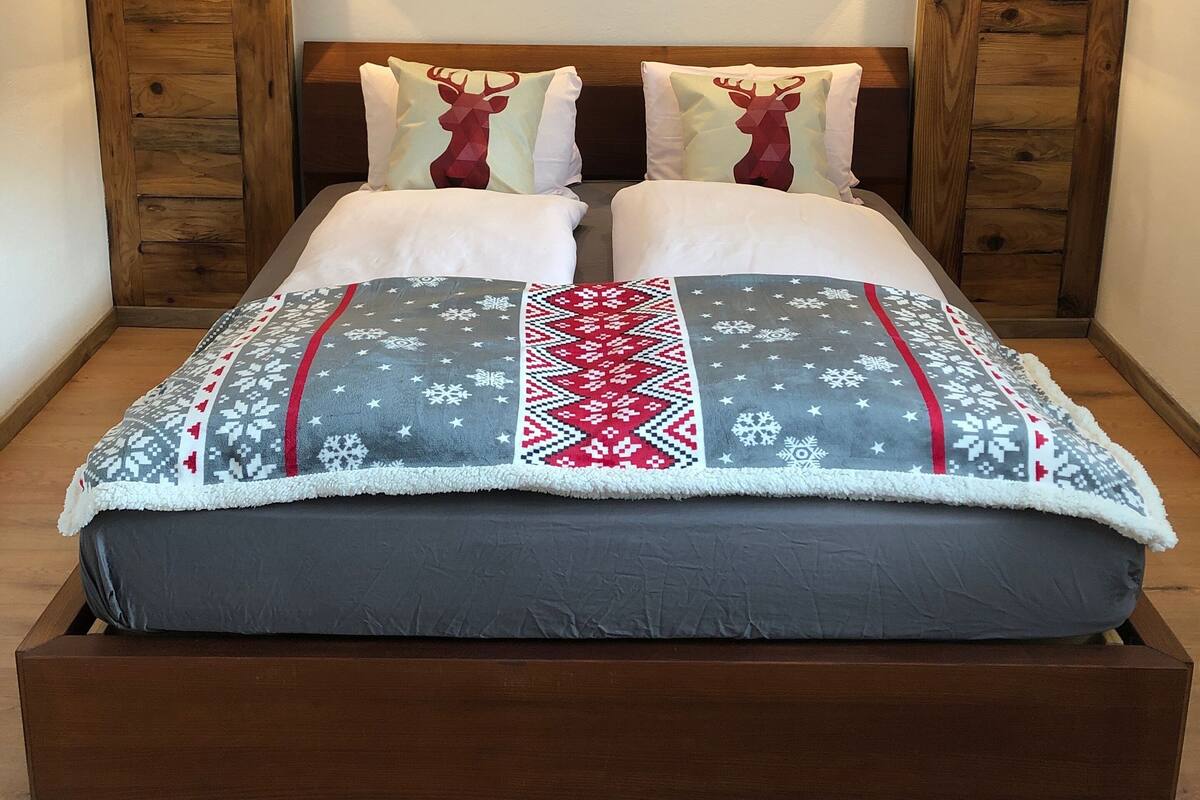 A bed with a mountain view backdrop, wooden headboard, and two bedside lamps.