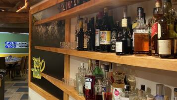 Eine Bar mit Regalen voller Spirituosenflaschen, Gläsern und einem roten Korb.