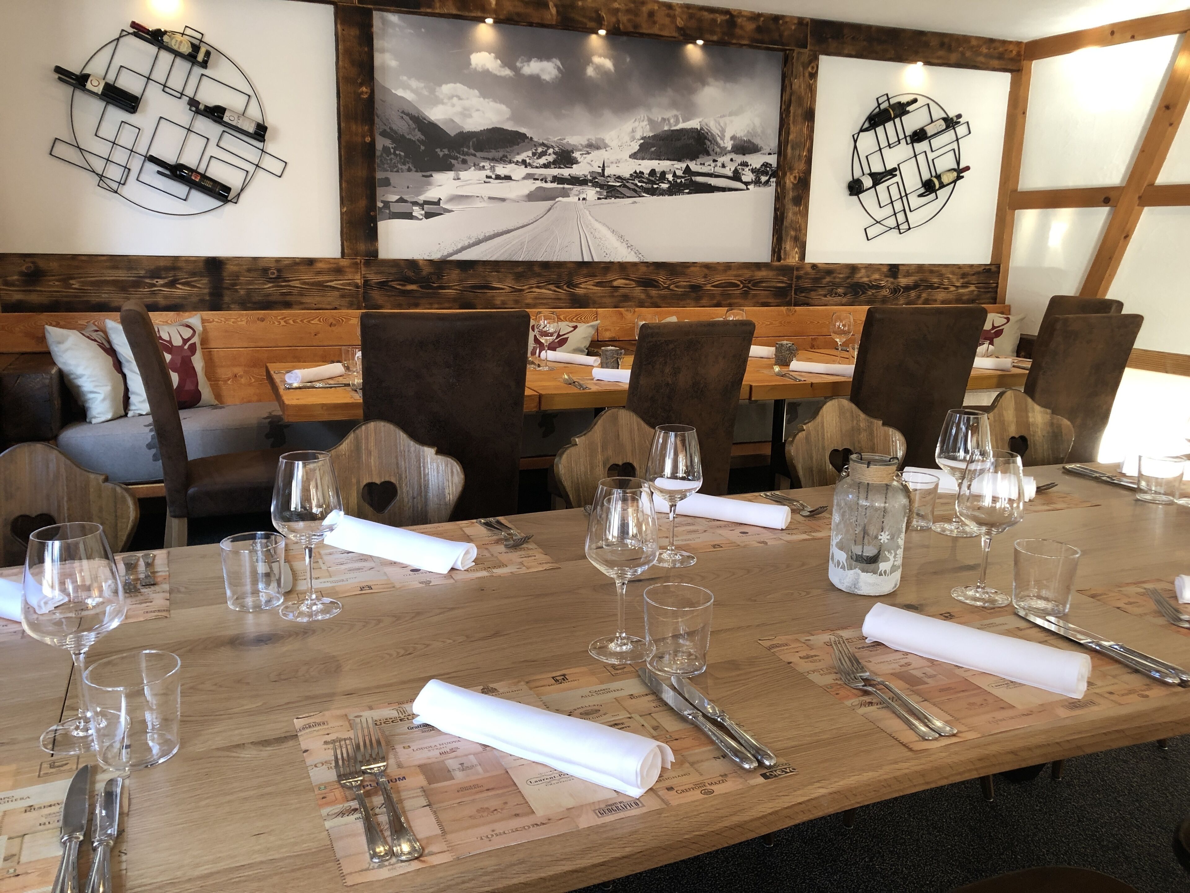 Een restaurant met houten tafels en stoelen, wijnglazen en een grote zwart-witfoto aan de muur.