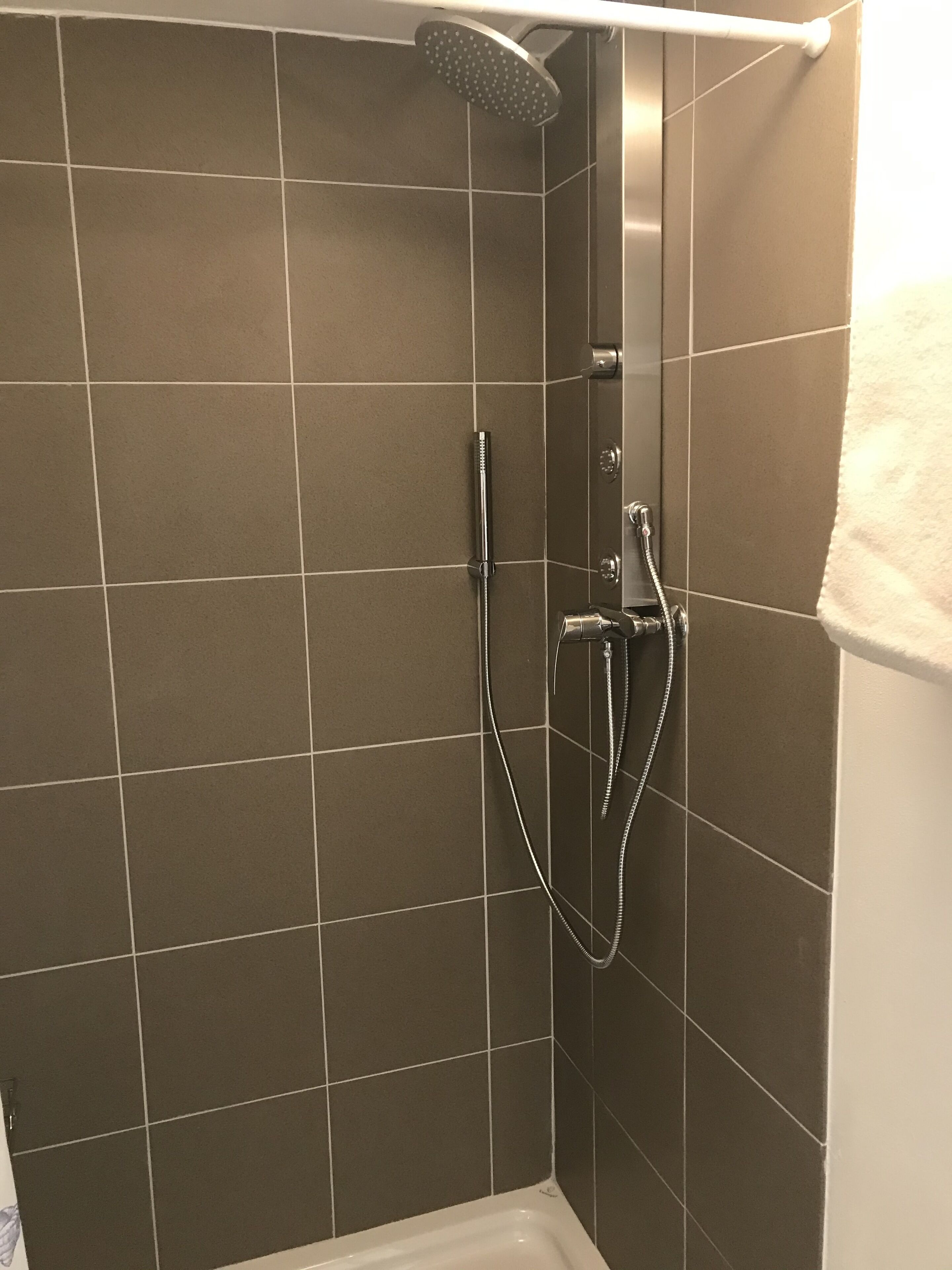 Zona de ducha con cabezal de ducha de mano y grifo empotrado.