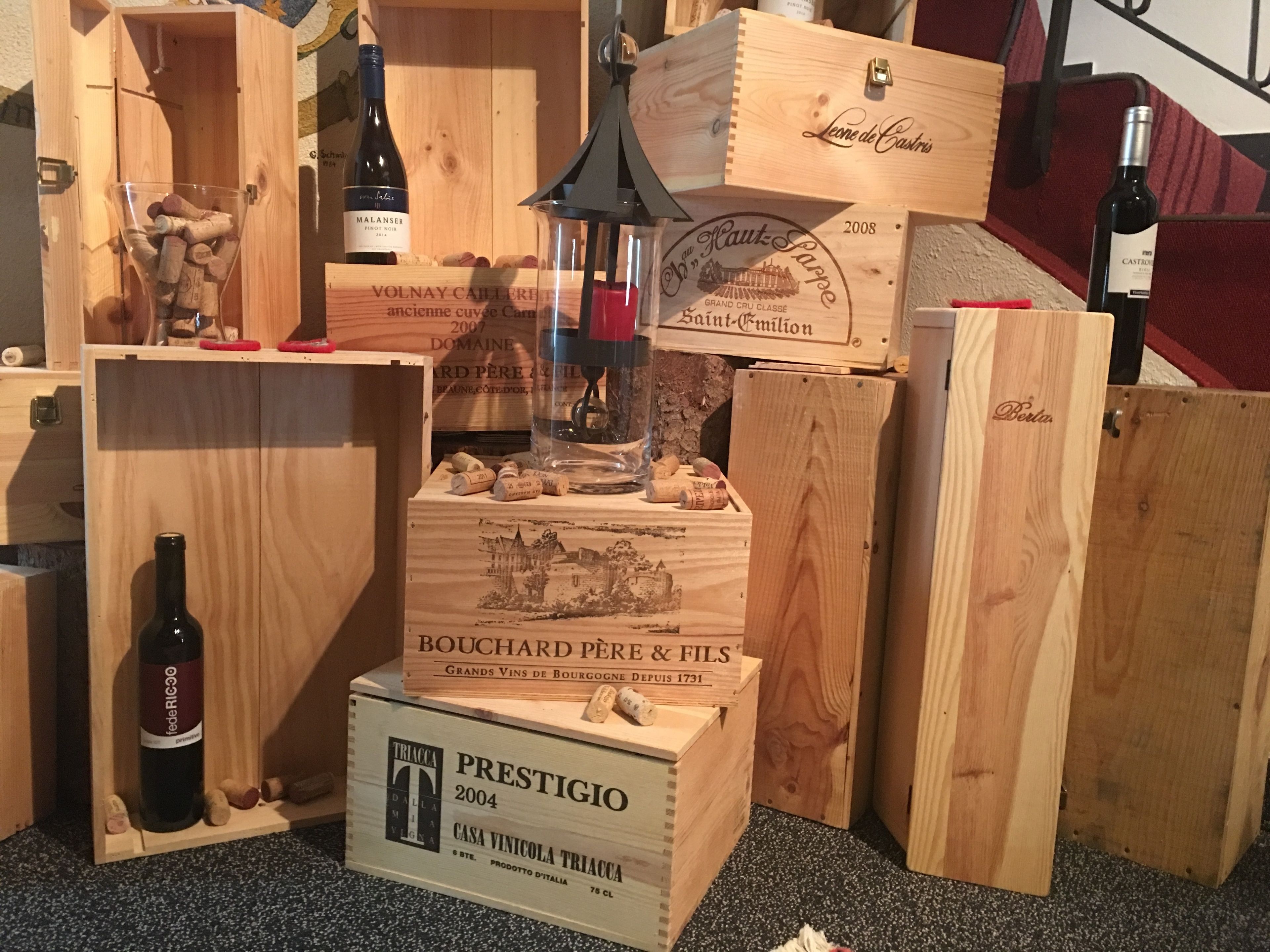 A collection of wooden wine boxes and bottles, some labeled with vintage years and names.