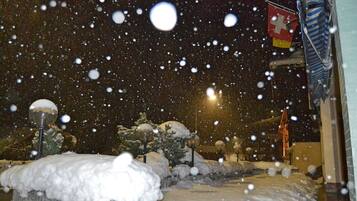 A snowy night scene with snow-covered ground and street lamps.