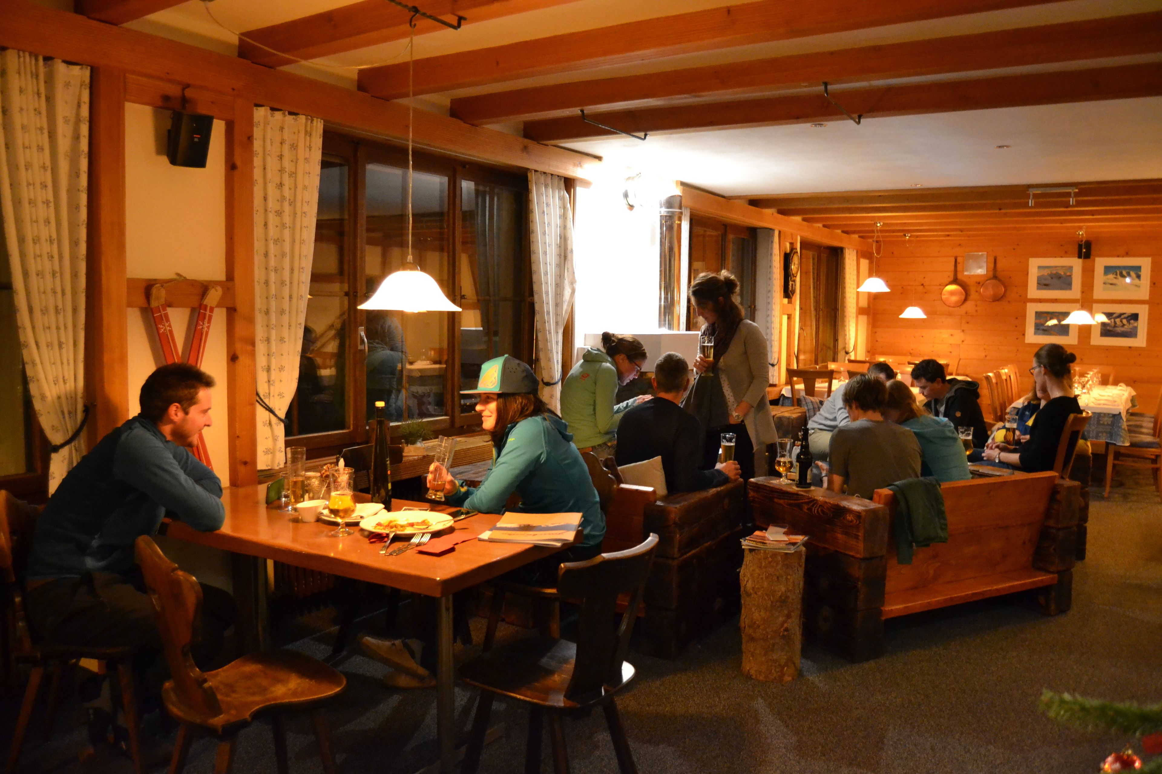 Un restaurante acogedor con muebles de madera, una mesa larga compartida y cabinas individuales.