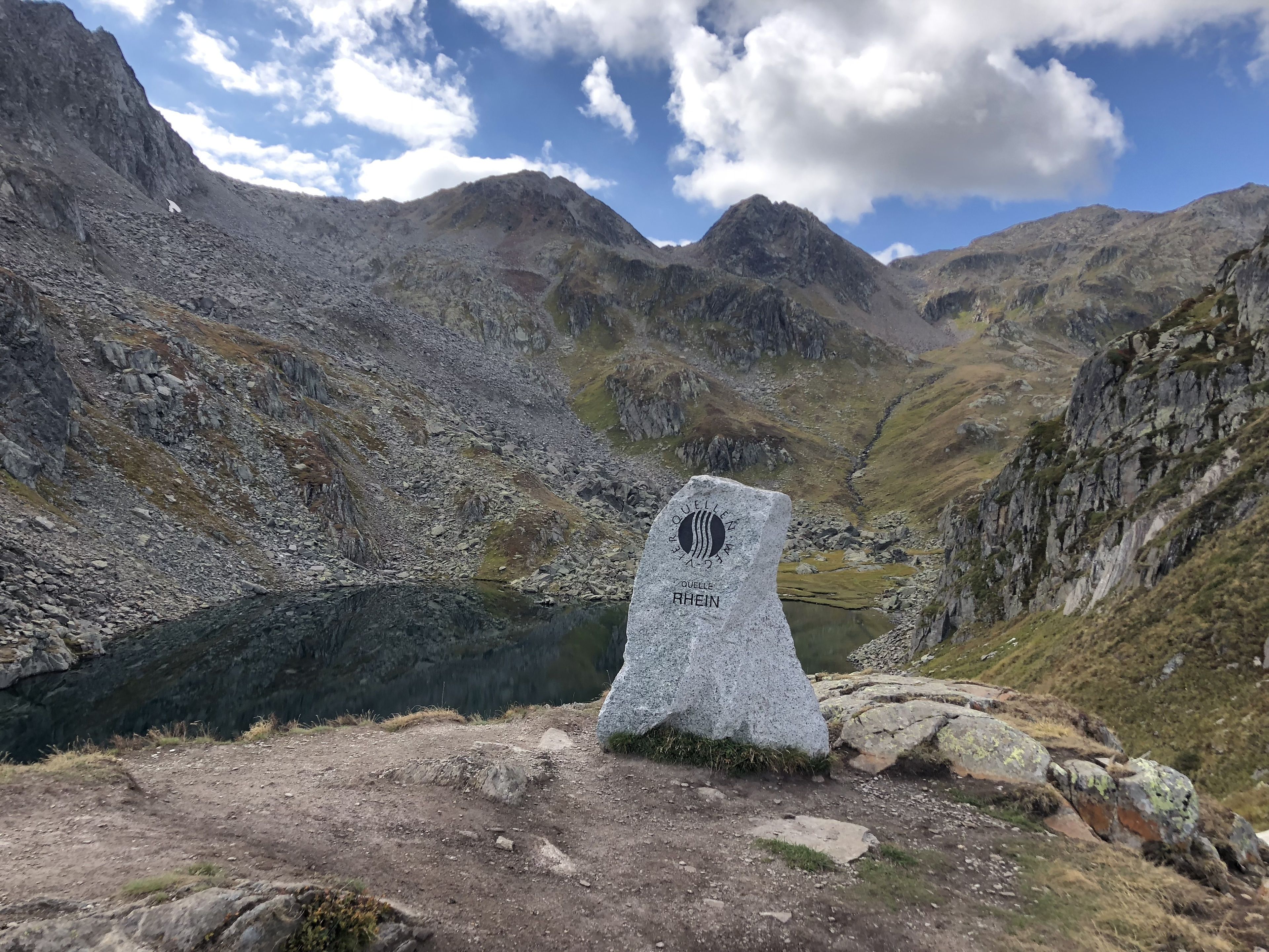 A mountain peak with a cairn and a lake in the valley.
