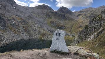 A mountain peak with a cairn and a lake in the valley.