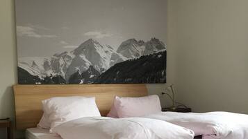 Ein hölzernes Bett mit zwei Kissen, einem Nachttisch und einer Wandlampe.