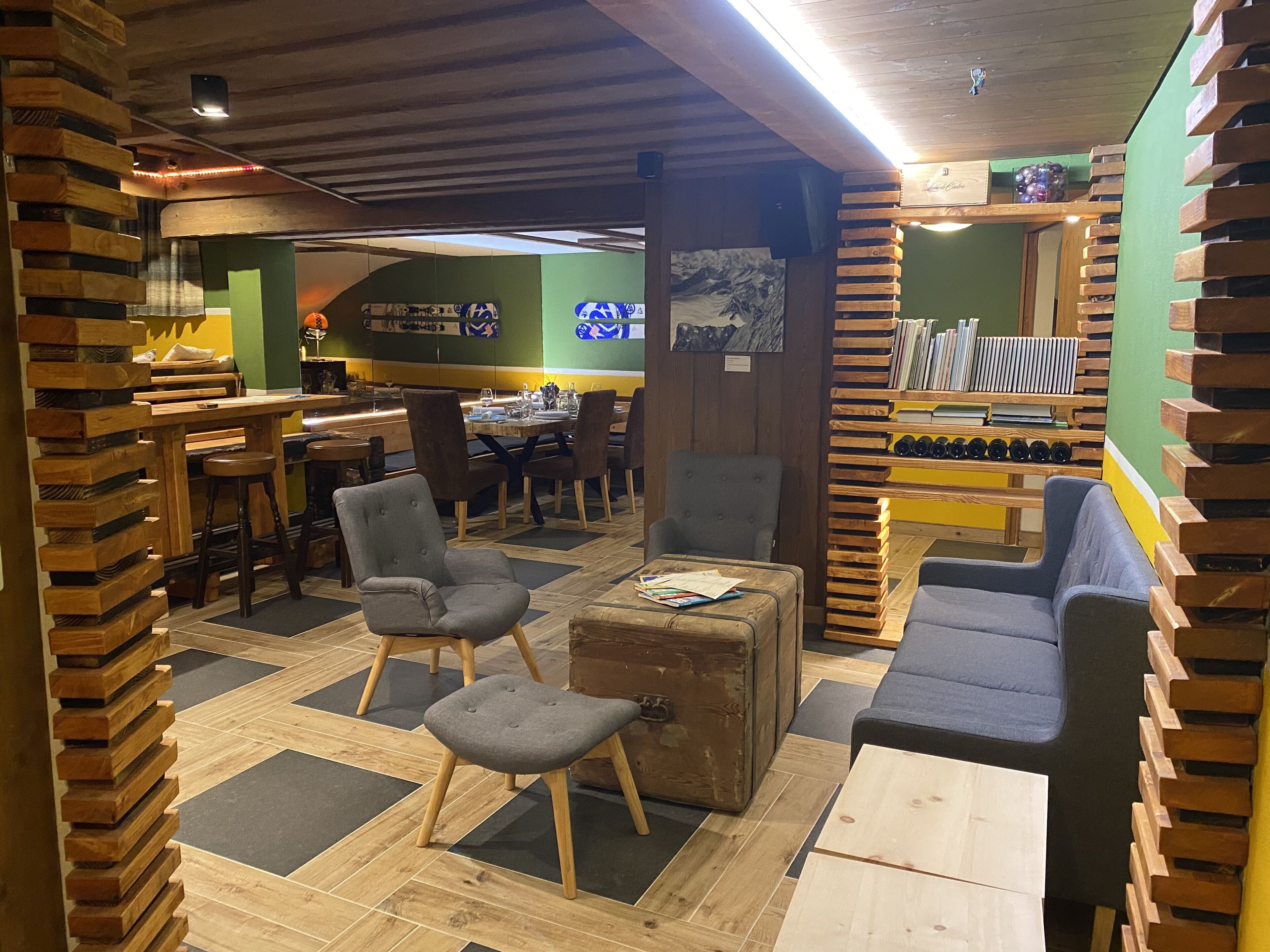 En mysig restaurang med träinredning, en bardisk och en sittgrupp med en soffa och stolar.