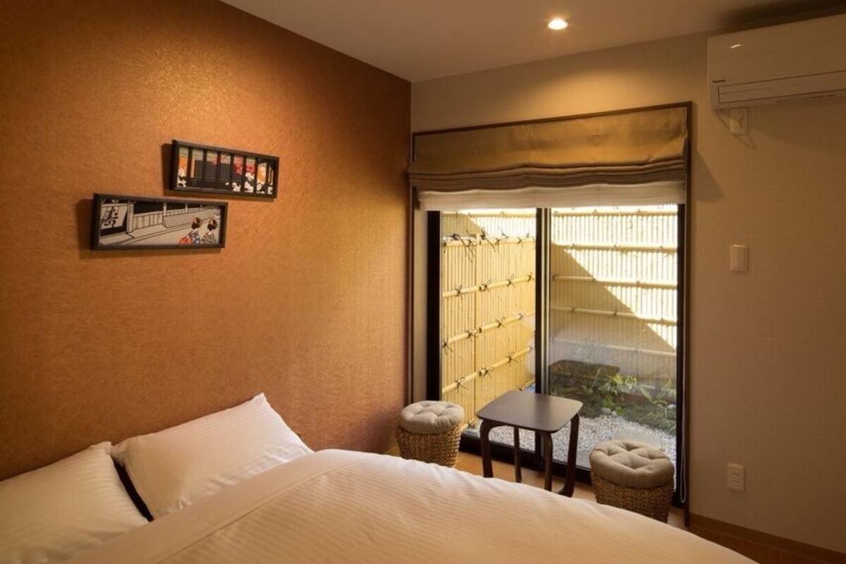 Een hotelkamer met een bed, een tafeltje, twee stoelen, een schuifdeur naar een balkon en kunst aan de muur.