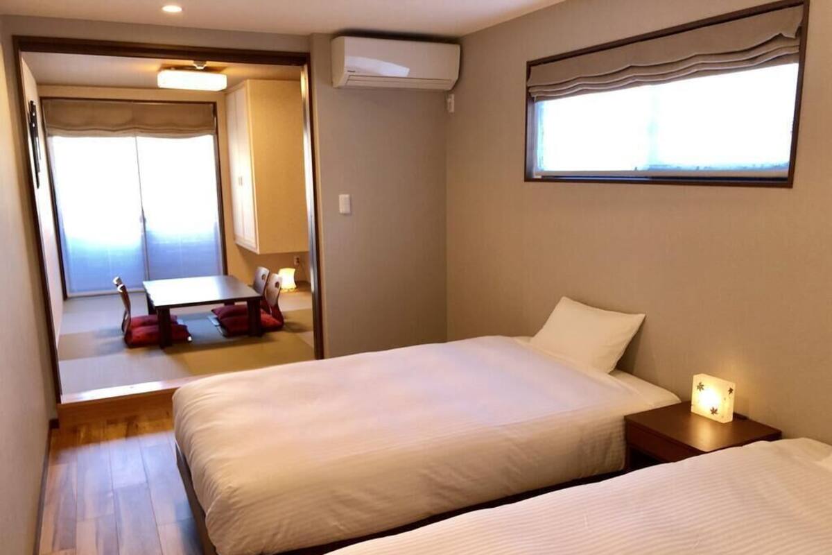 Een hotelkamer met twee bedden, een kleine tafel en een raam met gordijnen.