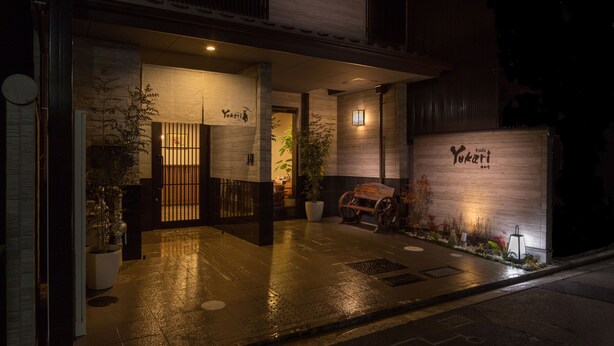 A traditional Japanese restaurant entrance with a wooden exterior, a signboard, and a potted plant. - Yukari Kyoto (Kyoto)