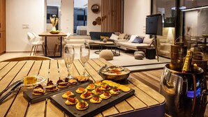A modern living room with a dining area featuring a wooden table set for a meal, a sofa, and a TV. - Sun n Chill (Corfu)
